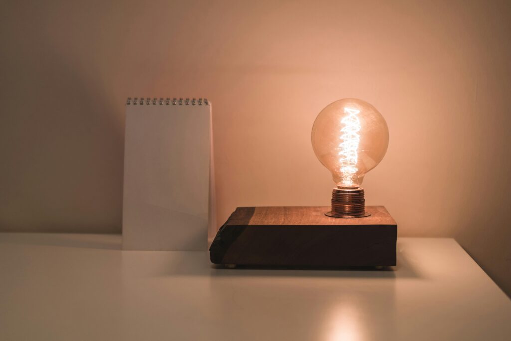 A minimalist setting featuring an Edison bulb lamp and a blank notepad on a white desk, perfect for conceptual ideas.